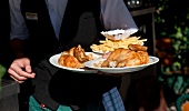 Waiter holding plate with half chicken and chips in Swiss House