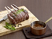 Venison meat on chopping board with dark sauce in sauce pan
