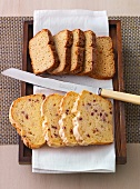 Wholemeal bread and onion-bacon bread with knife in wooden tray