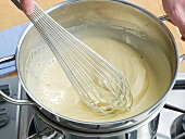 Whisking egg yolk-sugar mixture in pan for preparation of zabaglione, step 4