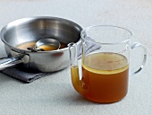Removing grease by beaker from cold broth in pan, method 2