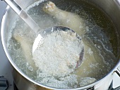 Removing froth with ladle from pan for preparation of chicken stock, step 3