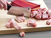 Cutting veal pieces on wooden board for preparation of veal stock, step 1