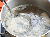 Close-up of froth being removed with sieve for preparation of beef stock, step 4