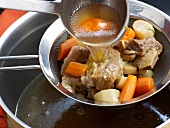 Close-up of stock being poured in sieve for preparation of beef stock, step 6