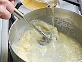 Close-up of liquid being poured in mixture for preparation of poultry veloute, step 2