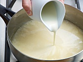 Close-up of cream being poured in mixture for preparation of poultry veloute, step 4