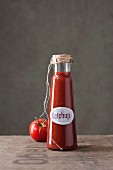 A bottle of homemade ketchup and a tomato