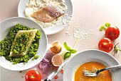 Fish fillets with bread crumbs on plate besides vegetables on white background