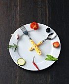 Expresskochen: Symbolische Uhr aus Teller, Obst Gemüse & Besteck