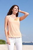 Beautiful woman with brown hair wearing orange sleeveless blouse looking away, smiling