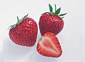 Whole and halved elsanta strawberry on white background