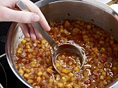 Close-up of nectarines and ginger chutney being stirred with ladle in casserole, step 4