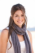 Portrait of beautiful brunette woman wearing white top and gray scarf, smiling