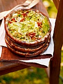 Stack of fennel gratin with mushrooms on wooden chair, garden kitchen