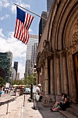 Tourists sitting outside Saint Bartholomew's Episcopal Church in Manhattan, New York, USA