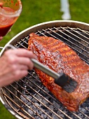 Close-up of ribs being brushed with sauce