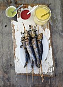Grilled sardines on sticks with various dips