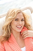 Portrait of happy blonde woman wearing salmon coloured sweater, laughing