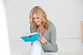 Blonde woman engrossed in reading John Wilde's book, smiling