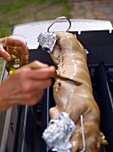 Applying oil on stuffed suckling pig