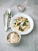 Chicken fricassee on plate with bowl of rice