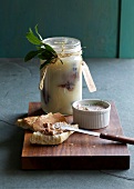 Homemade goose confit in jar and duck rillettes with bread on chopping board