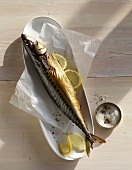 Homemade hot smoked mackerel with lemon slices in serving dish