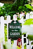 Wooden sign with welcome message on garden fence