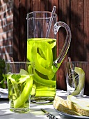 Melon juice with pieces of melon in carafe and glasses on table