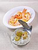 King prawns on plate with capers and olive aioli in glass bowl