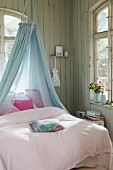 Fabric canopy above bed in wooden cabin