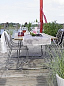 Table with dishes, chairs on terrace near water