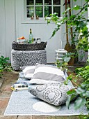 Outdoor rug and floor cushions in front of wicker tray on pouffe