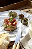 Salmon and tomato tartare on plate with courgette rolls and baguette
