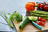 Fresh whole and sliced vegetables on chopping board