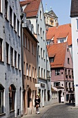Woman walking in alley at Pfladergasse, Augsburg, Bavaria, Germany