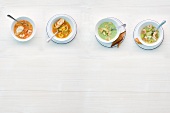 Four different type of soups with shrimp in bowls