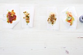 Four fish dishes on baking paper, overhead view