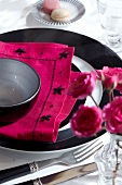 Pink napkin decorated with black flower motif on plate