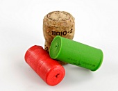 One natural cork with red and green plastic corks on white background