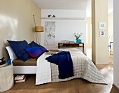 Bedroom with bed, blanket and pillows on wooden floor