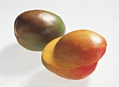 Whole and halves of mangoes on white background