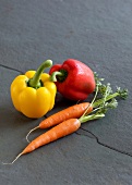 Fresh pepper and carrots on gray surface