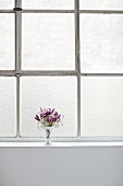 ein kleiner Blumenstrauß in einer Vase steht auf dem Fensterbrett