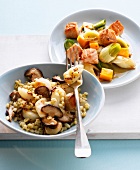 Leeks with artichokes and salmon with wheat and mushrooms on plates