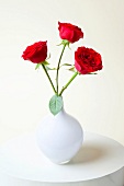 Close-up of three red roses in white vase