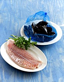 Fillet of pollock on plate and mussels in blue net