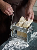 Close-up of dough being put through pasta maker while preparing pasta, step 2