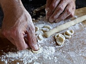 Close-up of hand pressing dough while preparing orecchiette pasta